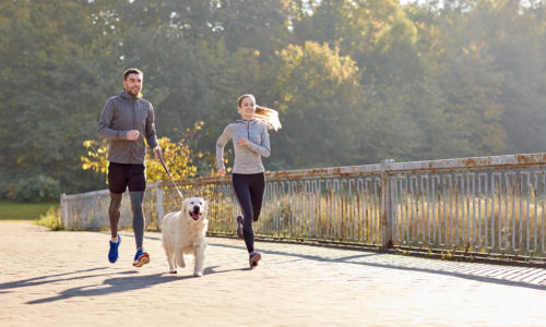 happy couple with dog running outdoors